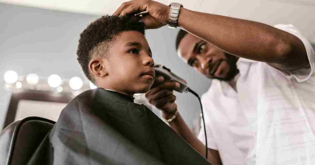 Barber creating a texture crop haircut for a boy, showing short textured top with clean faded sides for a modern and stylish look